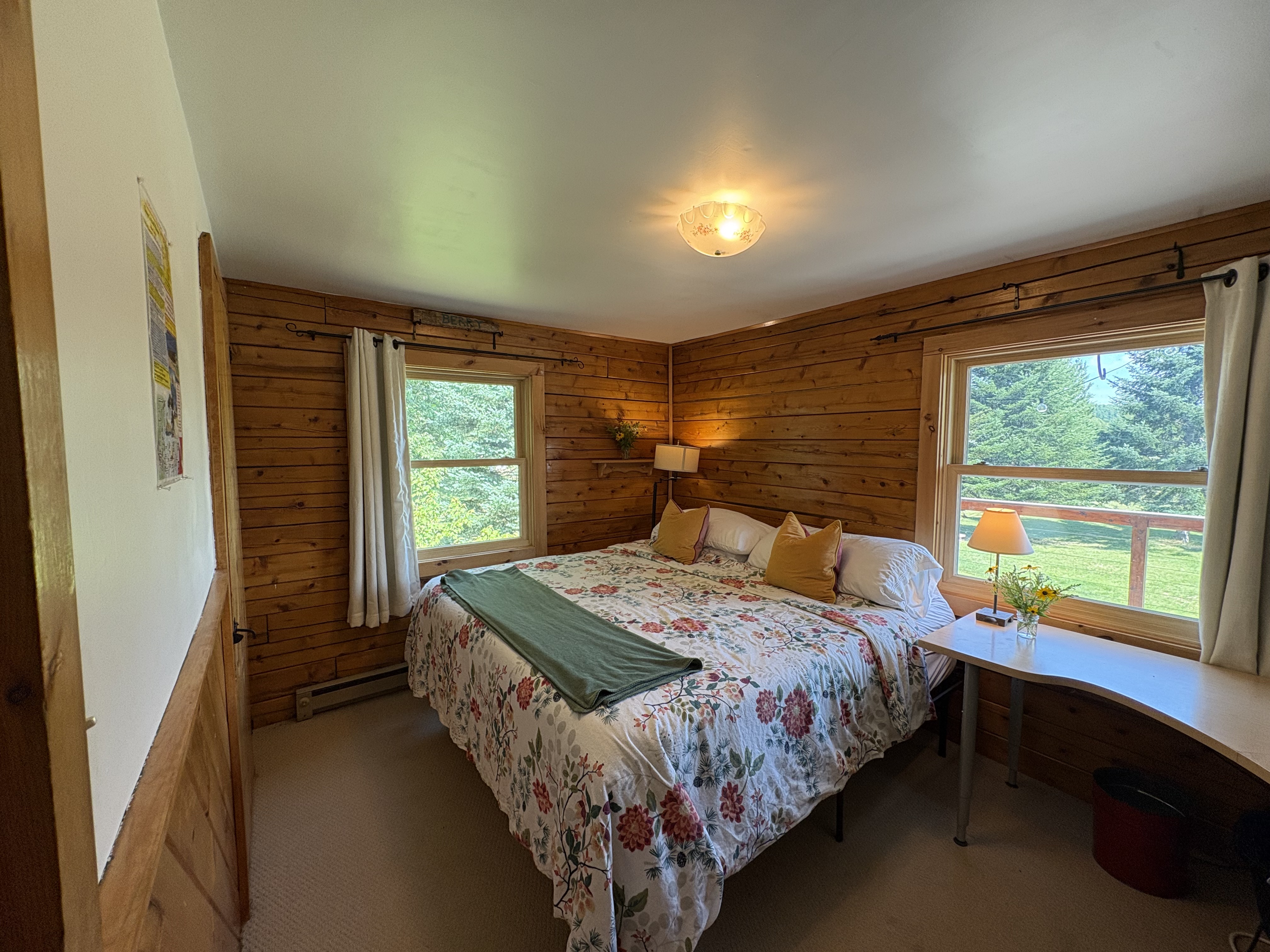 Upstairs king bedroom with wood walls and garden views