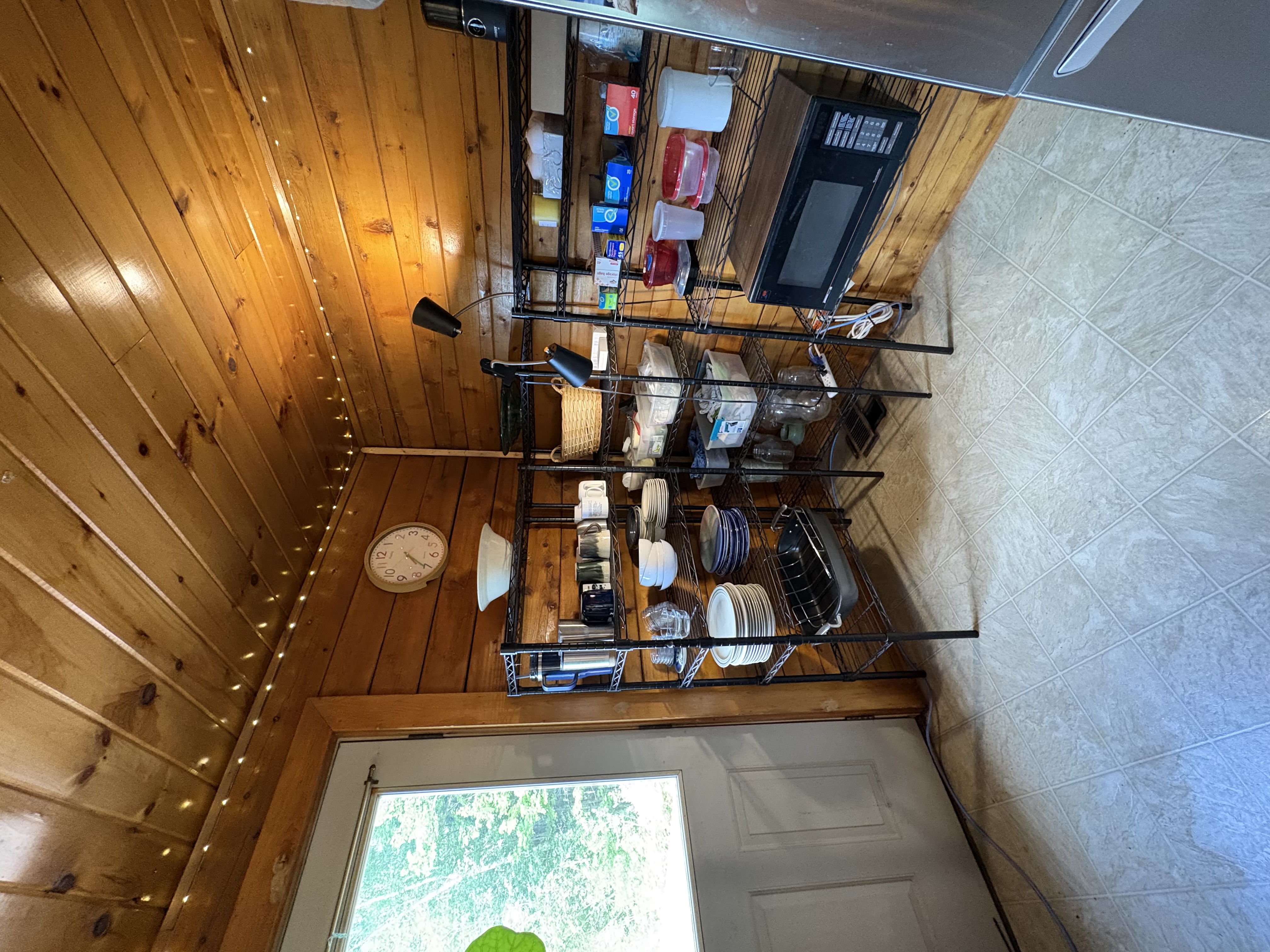 Fully stocked pantry shelves with dishes and microwave