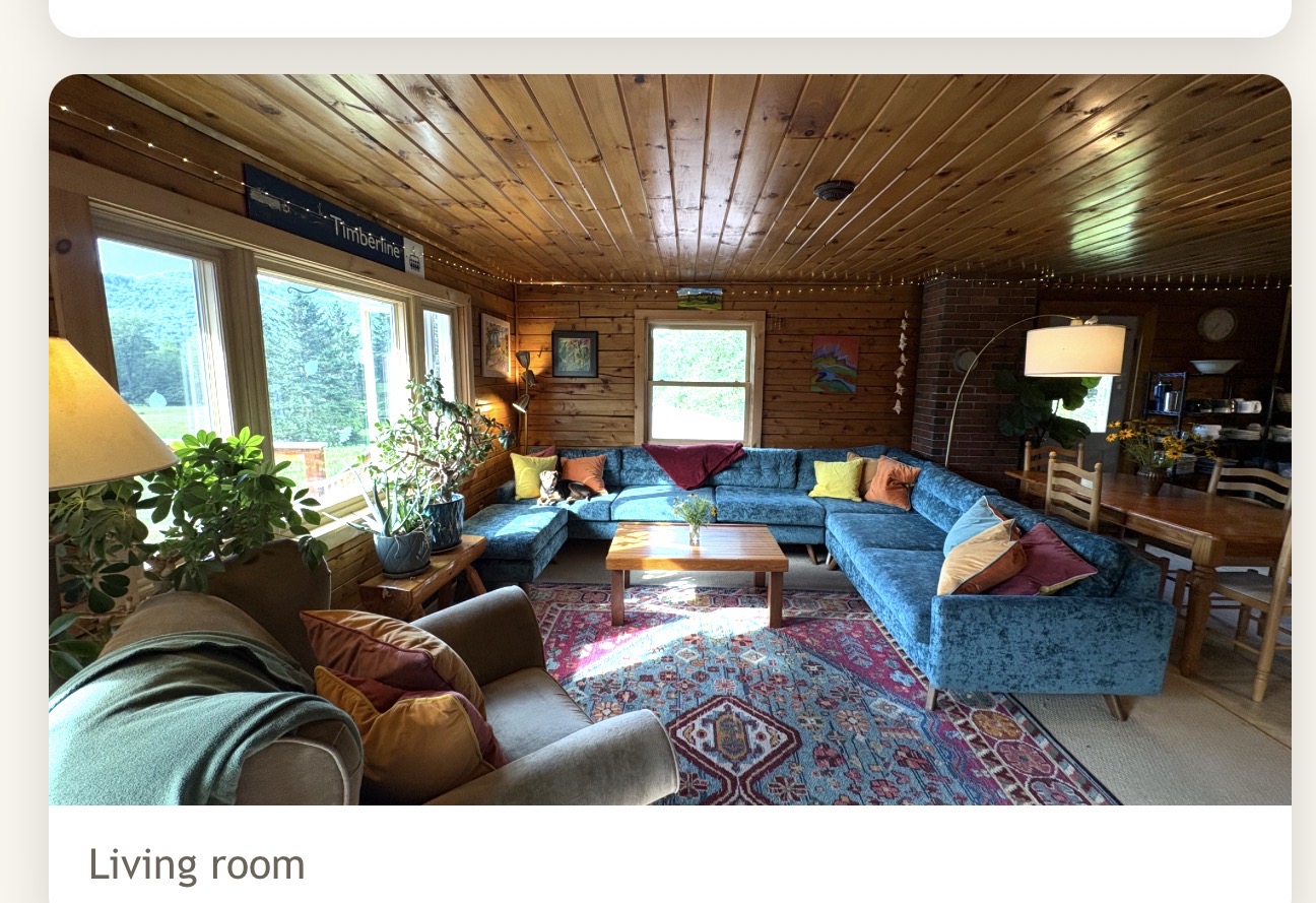 Spacious living room with large blue sectional sofa, wood ceiling and mountain views