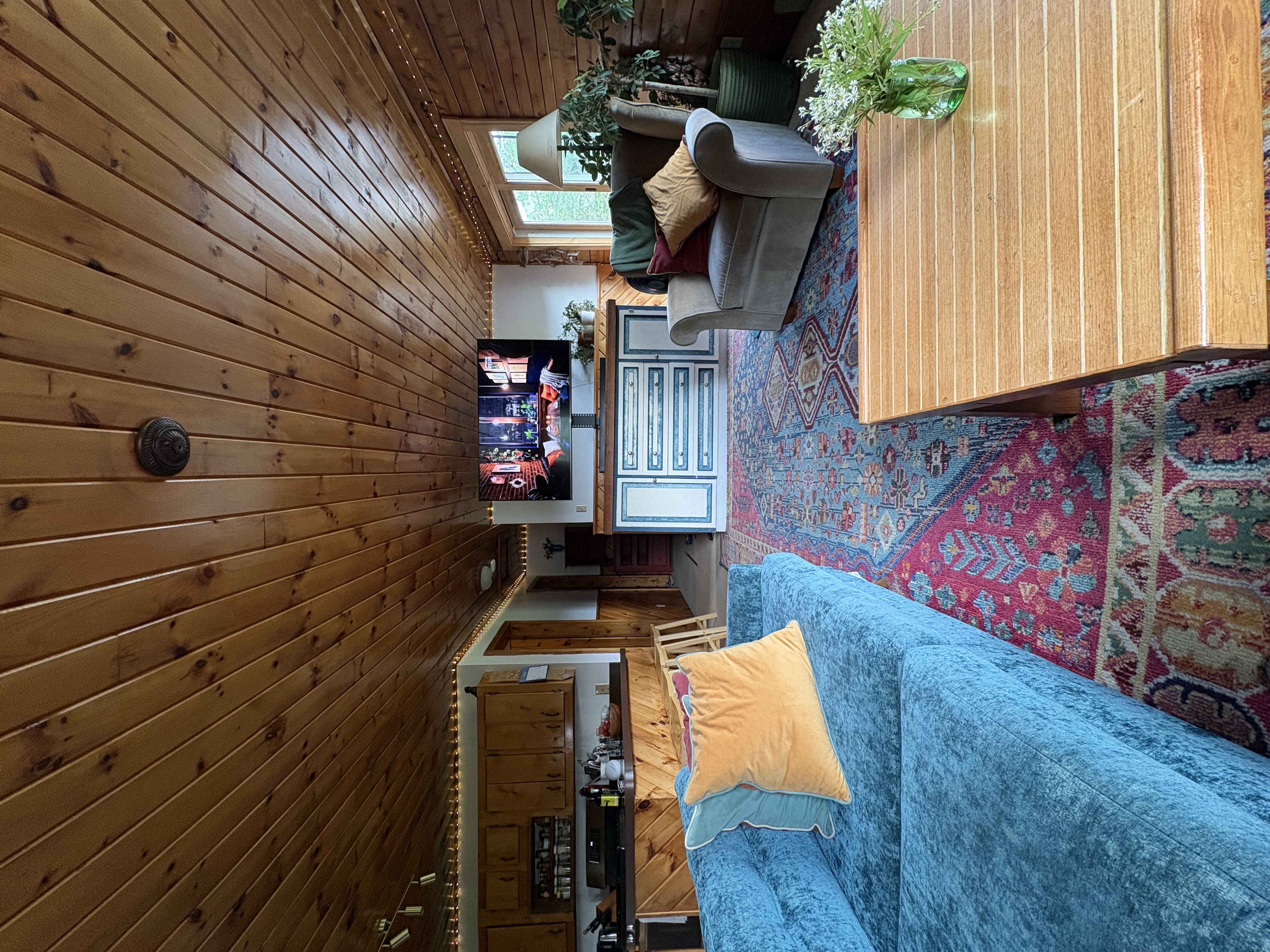 Wide view of living room showing sectional sofa, TV and kitchen beyond