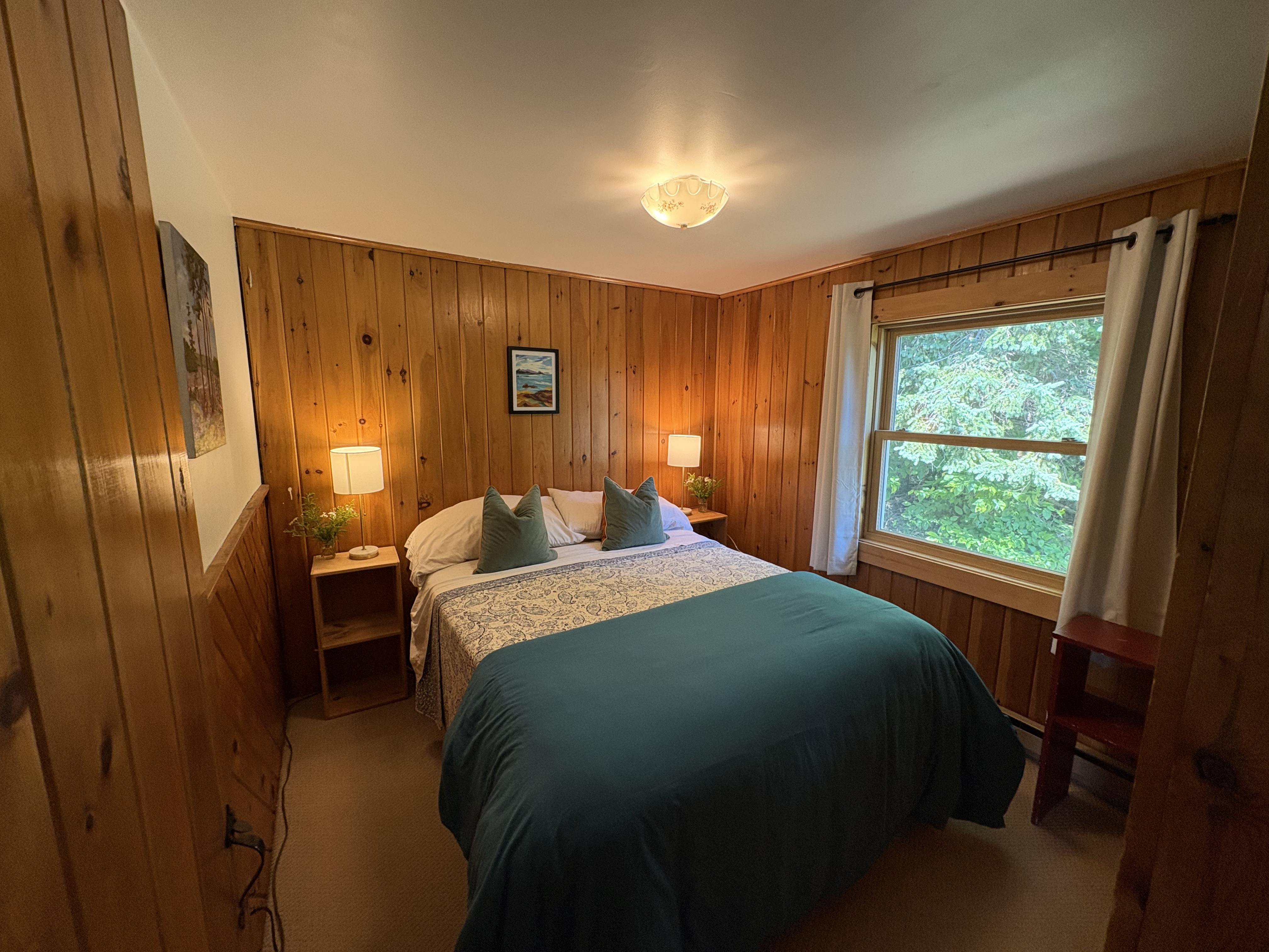 Queen bedroom with wood walls and garden window